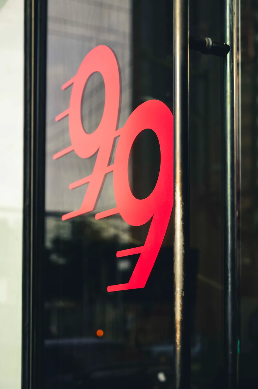Detalle del isotipo 99 rojo aplicado en el ventanal de Studio 99